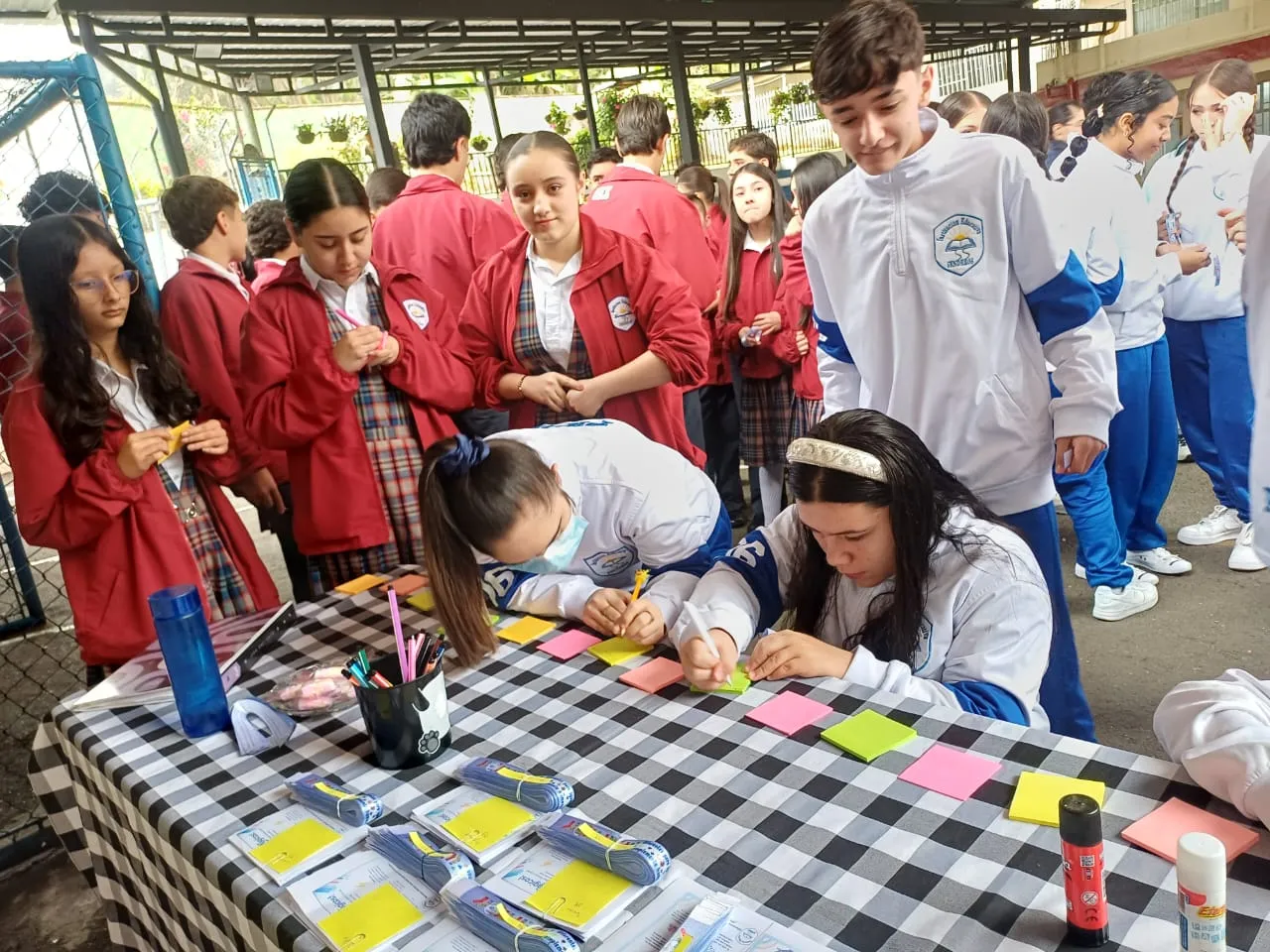 Estudiantes de distintos grados, con las chaquetas roja y azul del uniforme, comparten una actividad en el patio del colegio
